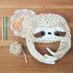 a crocheted hat with a slot face on it and some knitting needles next to it