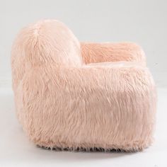 a pink bean bag chair sitting on top of a white floor next to a wall