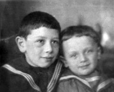 an old photo of two boys in sailor's outfits, one is hugging the other