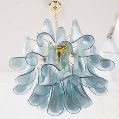 a blue chandelier hanging from a ceiling in a room with white walls and flooring