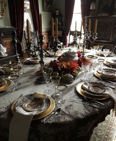 the table is set with plates, silverware and candlesticks for an elegant dinner