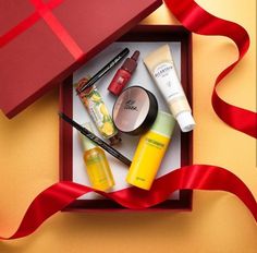 an open gift box with various beauty products in it and a red ribbon on the side