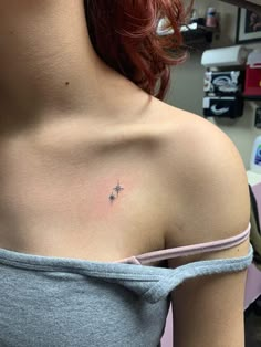 a woman with red hair has a small star tattoo on her left shoulder and chest