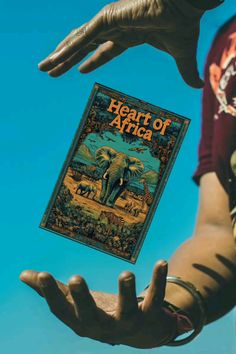 a person holding up a book with an elephant on it's cover in front of a blue sky