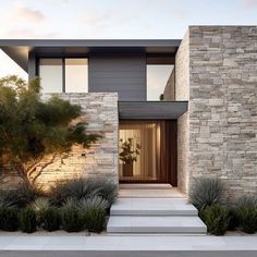 a modern house with stone walls and steps leading to the front door