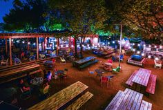 an outdoor seating area at night with lights on the tables and benches in the foreground