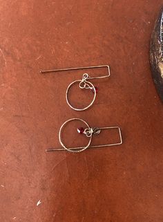 three pairs of earrings sitting on top of a brown table next to a black object