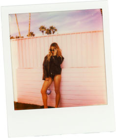 a polaroid photo of a woman leaning against a wall with her hand on her hip