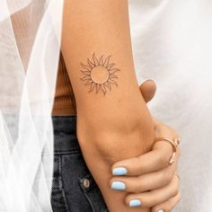 a woman's arm with a small sun tattoo on the left side of her arm