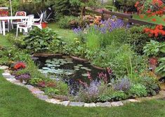 a garden filled with lots of flowers and plants next to a small pond in the middle of