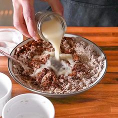 a person pouring milk into a bowl of food