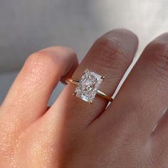 a woman's hand with a diamond ring on top of her finger and an engagement band