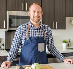 a man standing in front of a kitchen counter with an apple on the cutting board