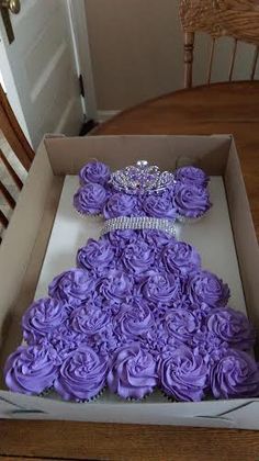 a box that has some purple cupcakes in it on top of a table