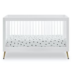 a white crib with black and white polka dots on the bedding, in front of a white background