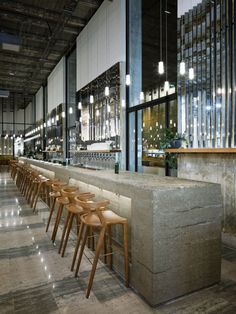 an empty bar with wooden stools and lights hanging from the ceiling in a restaurant