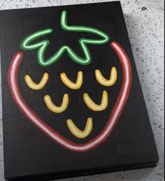 a painted strawberry on a black canvas with red, yellow and green neon lights in the shape of a heart