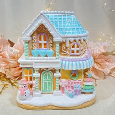 a gingerbread house is decorated with frosting and icing on the outside, along with pink flowers