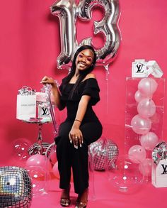 a woman sitting on a chair in front of balloons and presents for her 30th birthday