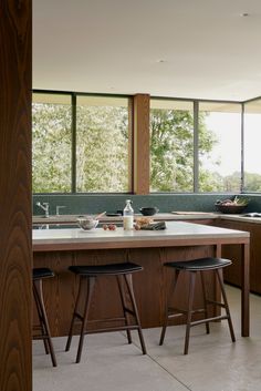 a kitchen with two stools next to an island in the middle of the room