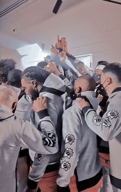 a group of young men standing next to each other in front of a mirror holding their hands up