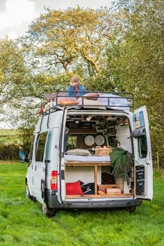 an old man sitting in the back of a van filled with furniture and supplies on top of it