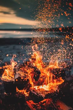 a campfire with lots of fire and water in the background