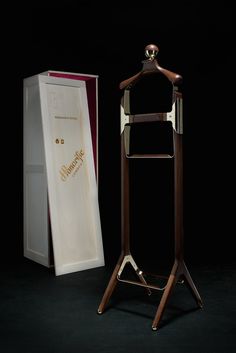 a wooden coat stand next to an open box on a black background with the door open