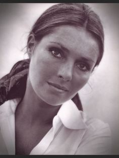 a black and white photo of a woman with her hair in a pony tail, looking at the camera