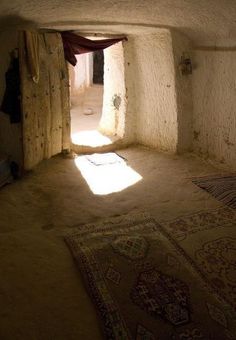 an empty room with sunlight coming in through the window and rugs on the floor