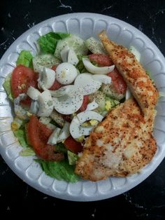 a white plate topped with salad and chicken