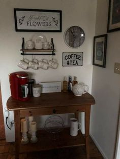 a wooden table topped with lots of cups and saucers next to a wall mounted clock