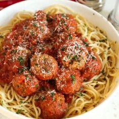 a bowl filled with spaghetti and meatballs covered in marinara sauce on top of it