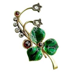 This is an exquisite and rare antique FABERGÉ Rose Cut Diamond, Enamel and Red Cabochon Brooch modeled as a sprig of flowers with a translucent green enameled flower centered with a red cabochon and the tendrils terminated in tulip form flowerheads set with rose cut diamonds and red cabochons. The brooch is hallmarked St. Petersburg 1896-1908, 56 gold standard and workmaster's initial AH for August Hollming. The spectacular jeweled and enameled flower motif brooch is a masterwork by one of Faber Faberge Jewelry, Flower Center, Flower Motif, Enamel Brooch, Royal Jewelry, Enamel Flower, Green Enamel, Rose Cut Diamond, Rare Antique