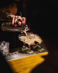 someone pouring drinks into glasses on a bar