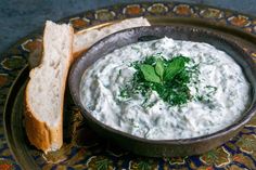 a bowl of dip with bread on the side and garnished with parsley