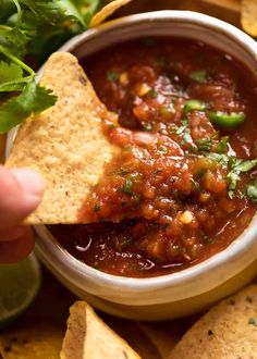 a tortilla chip being dipped with salsa