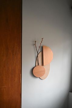 a wooden clock mounted to the side of a wall next to a vase with flowers