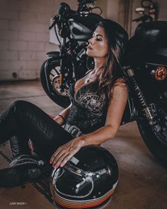 a woman sitting on the ground next to a motorcycle