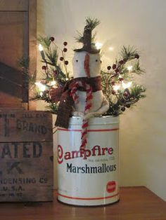 a tin can with a snowman in it sitting on a table next to a christmas tree