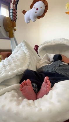 a baby is laying in a bed with stuffed animals hanging from the ceiling above him