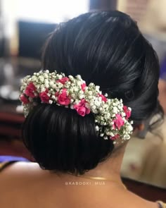 the back of a woman's head with pink and white flowers in her hair