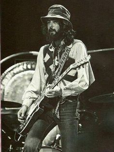 an old photo of a man with a hat and guitar in his hands on stage