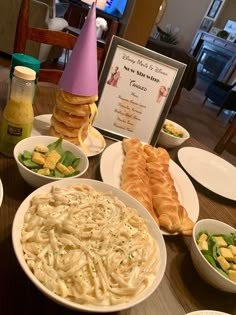 a table topped with plates of food and bowls of pasta next to a sign that says happy new year