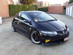 a black car parked in front of a brick building