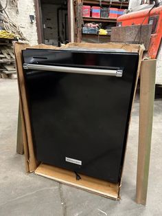 a black dishwasher sitting on top of a cardboard box in a warehouse area