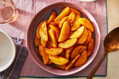 a bowl filled with sliced apples on top of a table next to plates and spoons