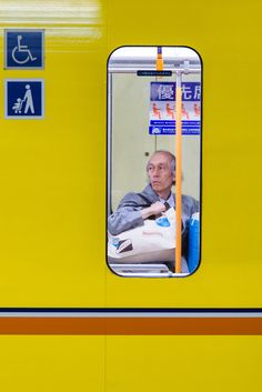 an older man sitting in a train looking out the window