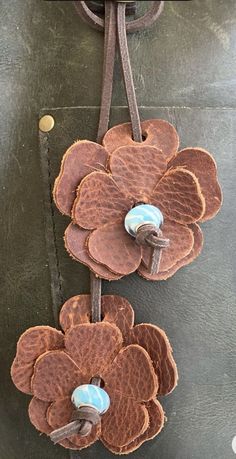 two flowers are attached to a brown leather belt with blue beads on it, hanging from a hook