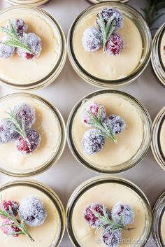 several desserts are arranged in small glass jars with cranberry toppings on top